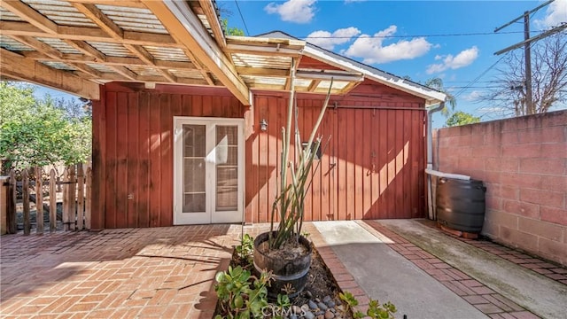 property entrance with a patio, board and batten siding, and fence