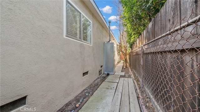 view of side of home with crawl space, stucco siding, and fence