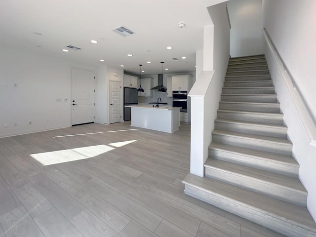 stairway featuring recessed lighting, visible vents, and wood finished floors