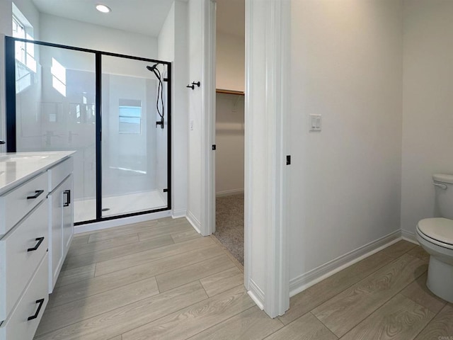 full bathroom with baseboards, toilet, a stall shower, wood finished floors, and vanity