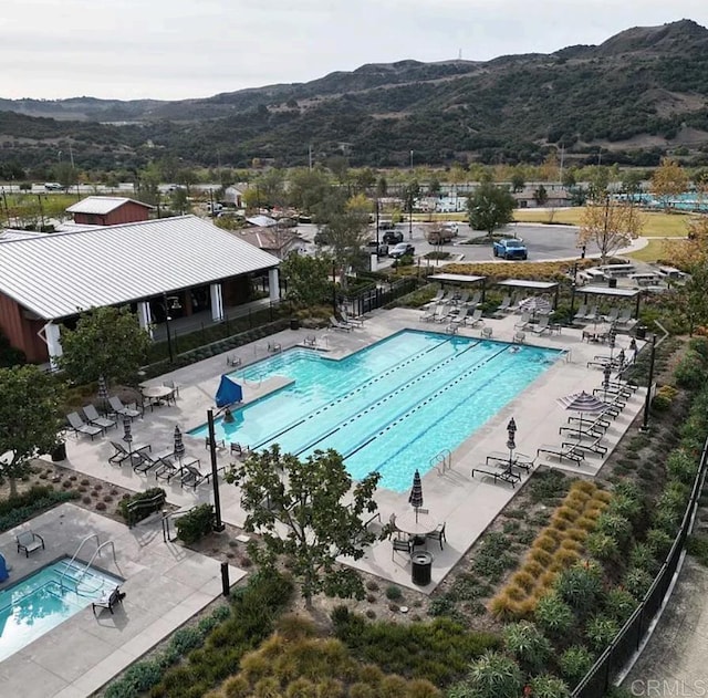 pool featuring a mountain view, a patio, and fence