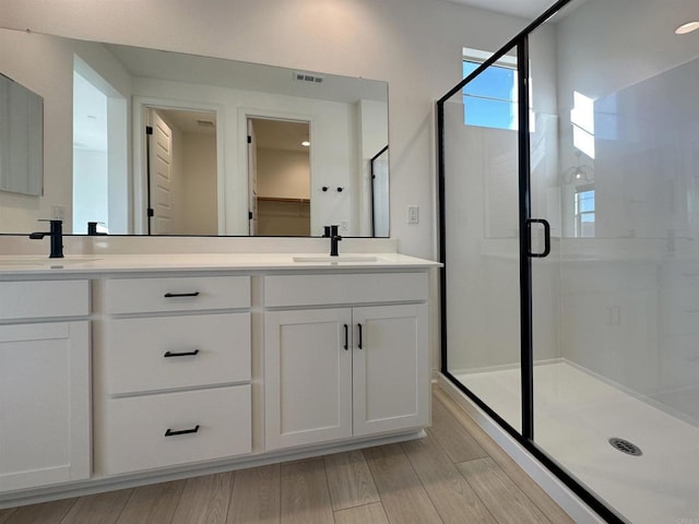 full bathroom featuring double vanity, visible vents, a stall shower, and a sink