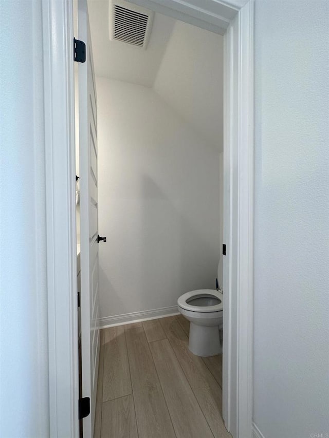 bathroom featuring visible vents, baseboards, toilet, and wood finished floors