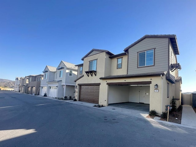 view of front of property with stucco siding, a residential view, and an attached garage