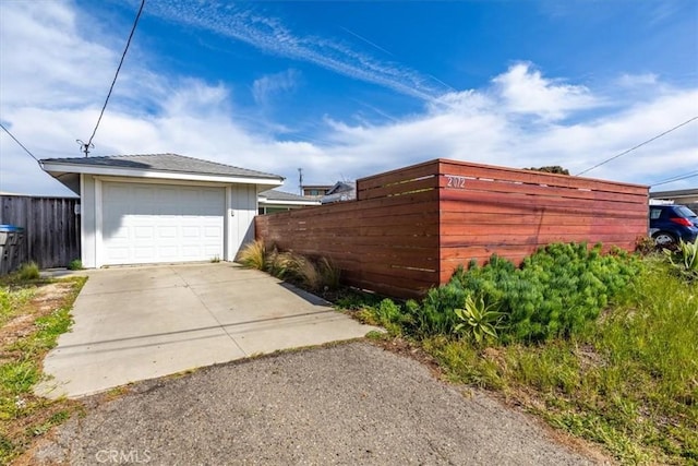 view of home's exterior featuring a garage, concrete driveway, and fence