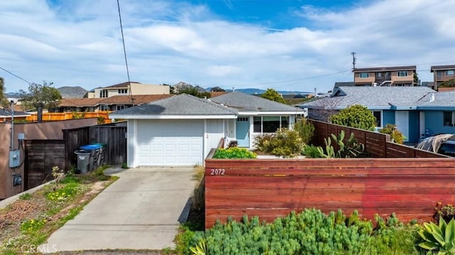 view of front of house with an attached garage, fence, a residential view, and driveway