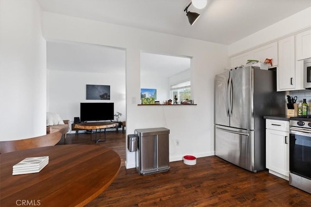 kitchen featuring dark countertops, dark wood-type flooring, decorative backsplash, appliances with stainless steel finishes, and white cabinetry