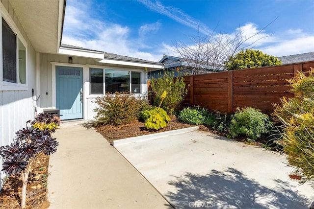 view of exterior entry with a patio and fence