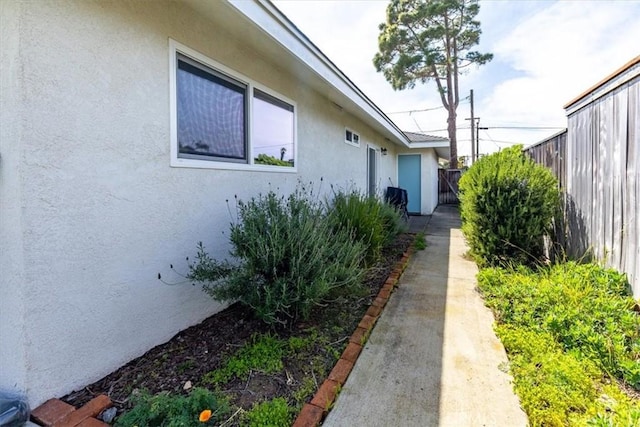 view of side of property with stucco siding and fence