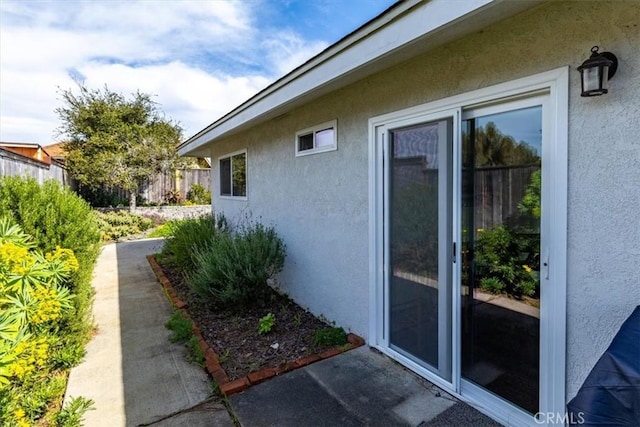 view of side of home with fence and stucco siding