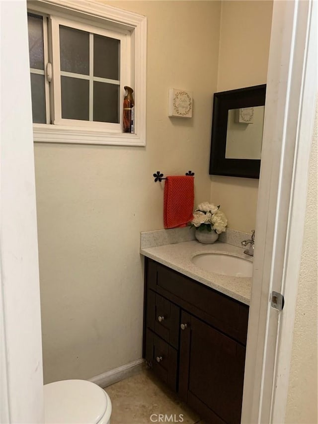 half bathroom featuring vanity, toilet, and baseboards