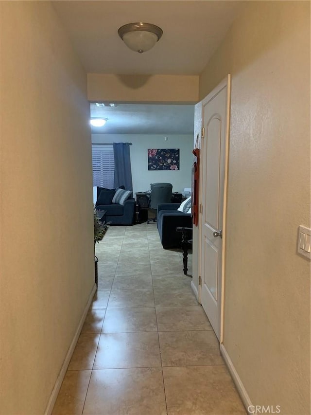 corridor with light tile patterned floors and baseboards