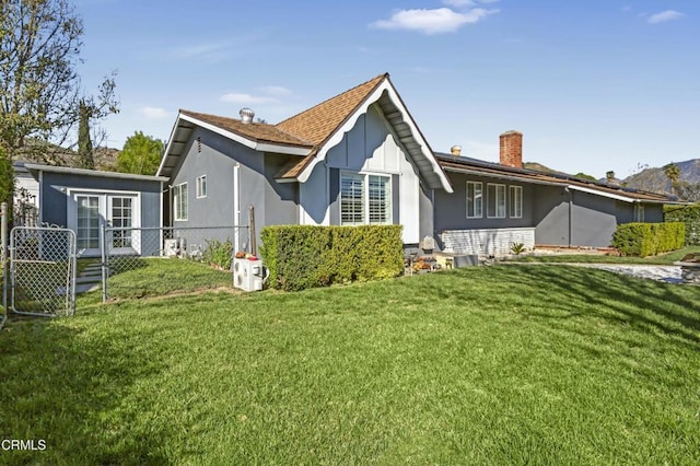 rear view of house featuring an outbuilding, a lawn, fence, french doors, and a chimney