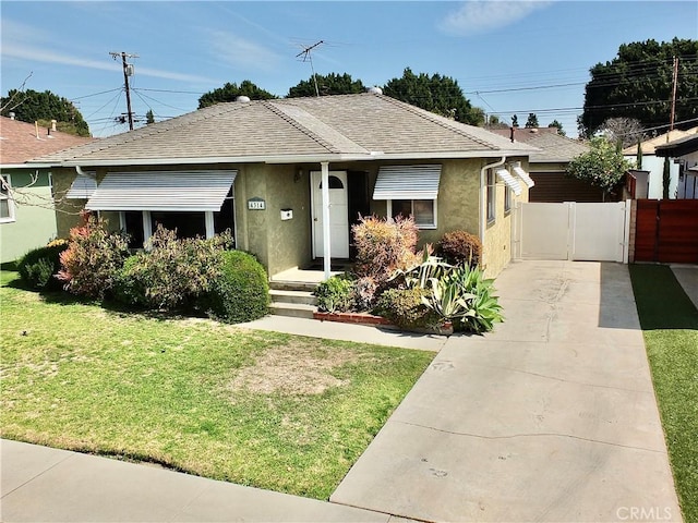 view of front facade with stucco siding, a gate, fence, roof with shingles, and a front yard