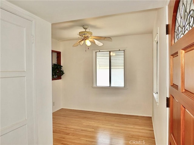 spare room with baseboards, a ceiling fan, and light wood finished floors