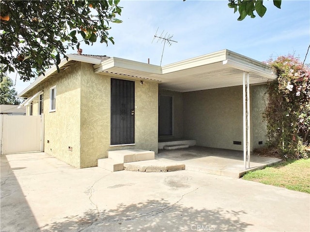 view of front of home featuring crawl space, stucco siding, a carport, and entry steps