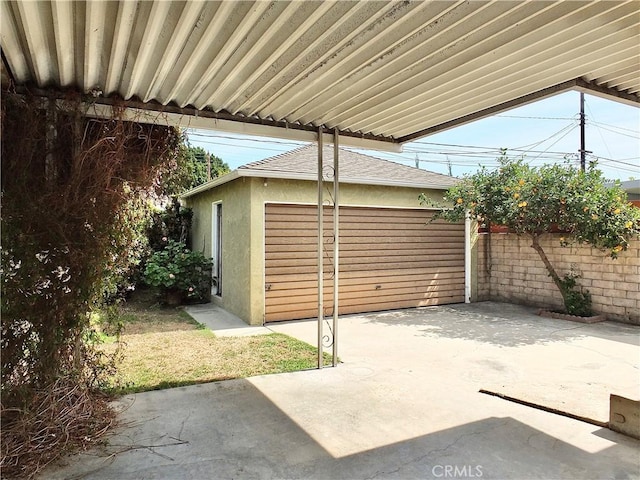 garage with concrete driveway and fence