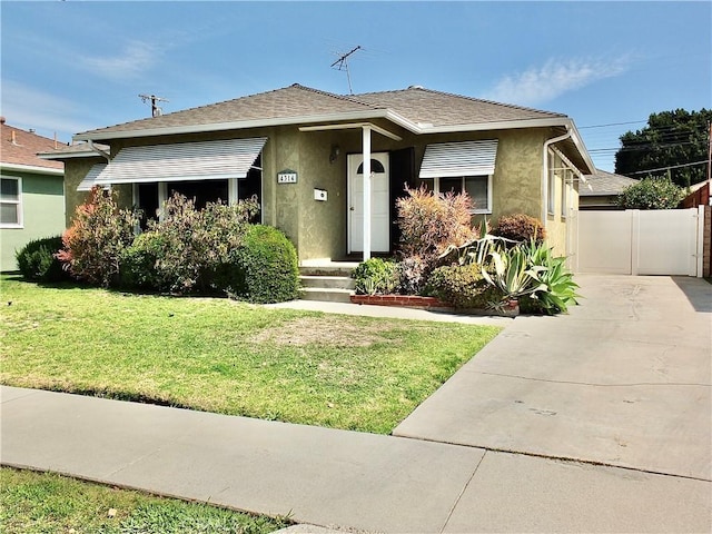 bungalow-style house featuring a front yard, roof with shingles, and stucco siding