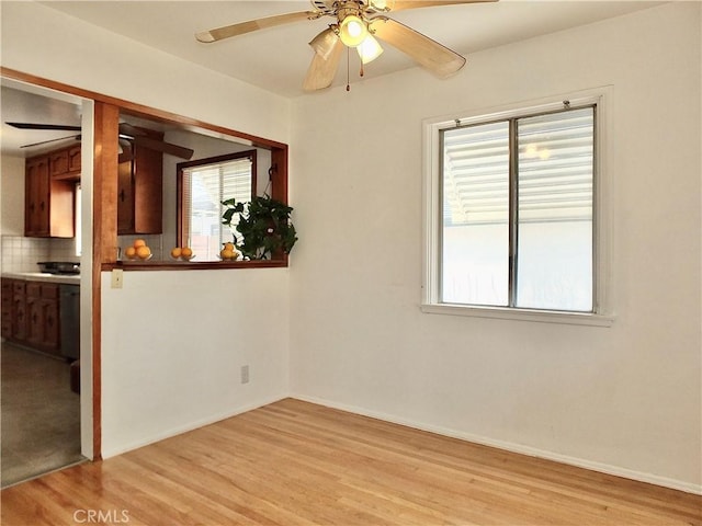 unfurnished room featuring a wealth of natural light, light wood-type flooring, baseboards, and ceiling fan