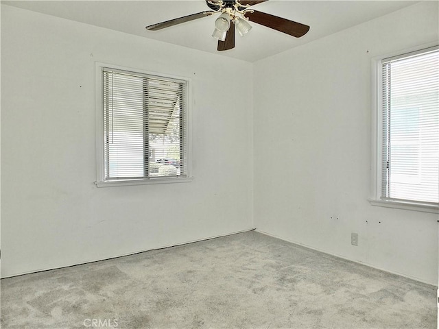 unfurnished room featuring a wealth of natural light, carpet, and a ceiling fan