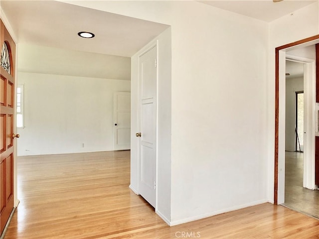 hallway featuring light wood-style flooring, baseboards, and a wealth of natural light