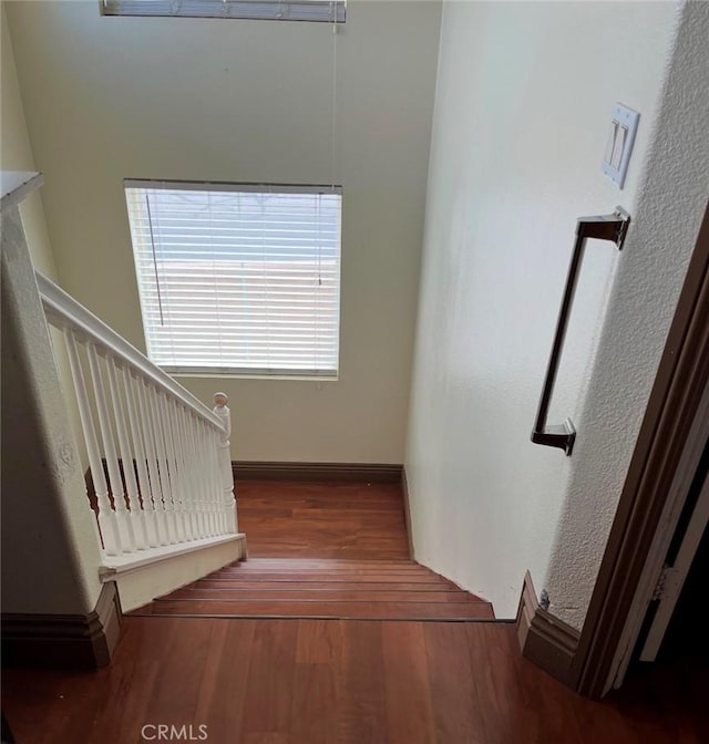 stairway with wood finished floors and baseboards