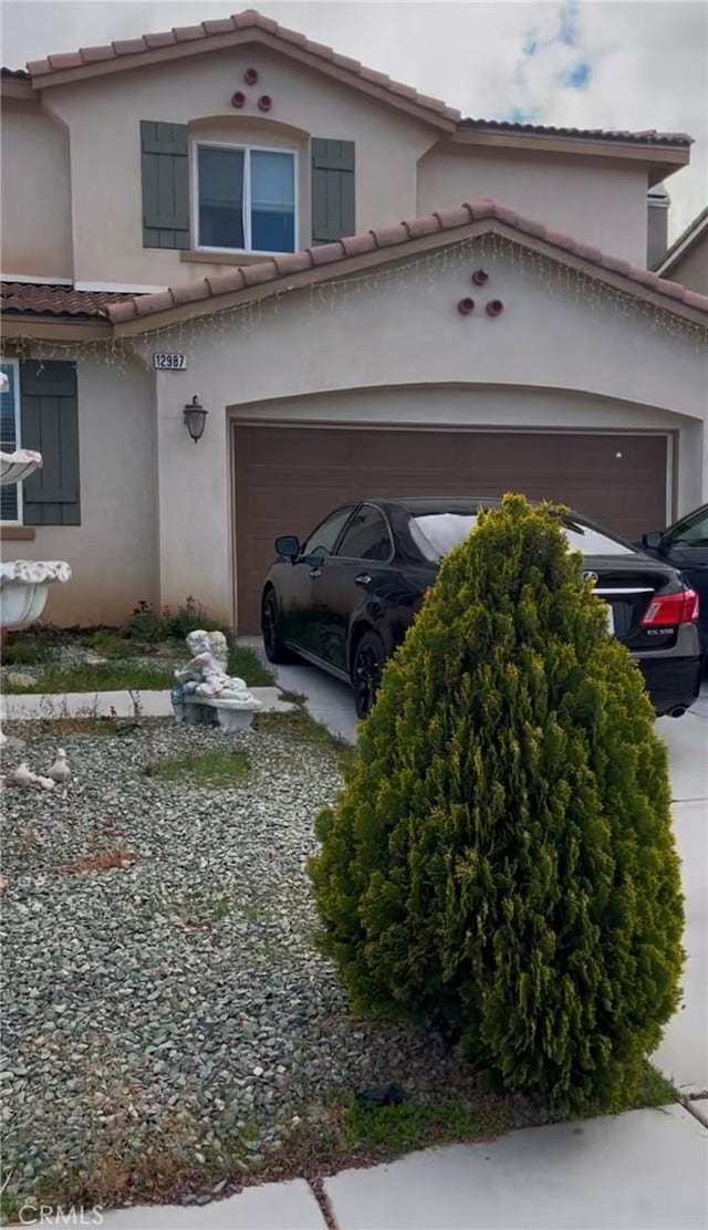 view of front facade featuring a garage, a tile roof, and stucco siding