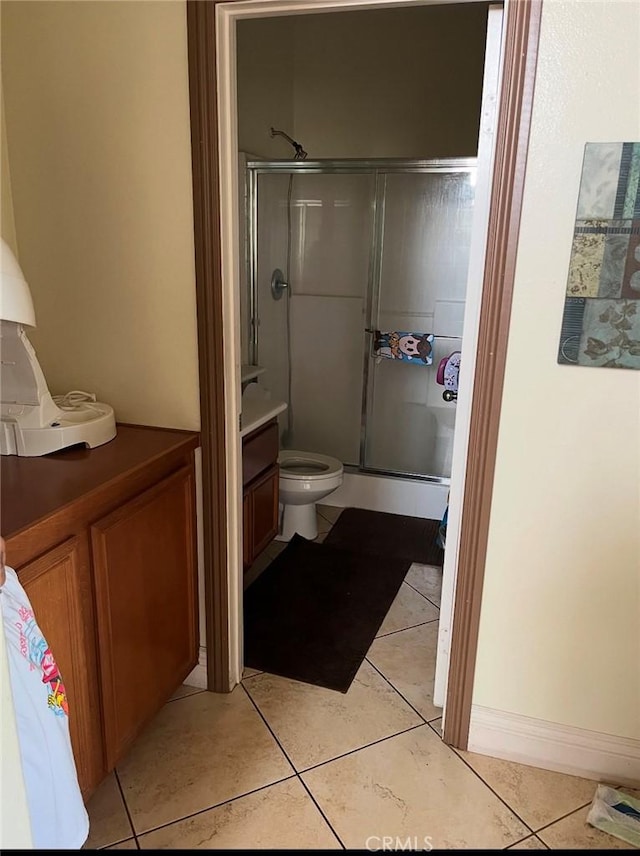 bathroom featuring tile patterned floors, a shower stall, and toilet