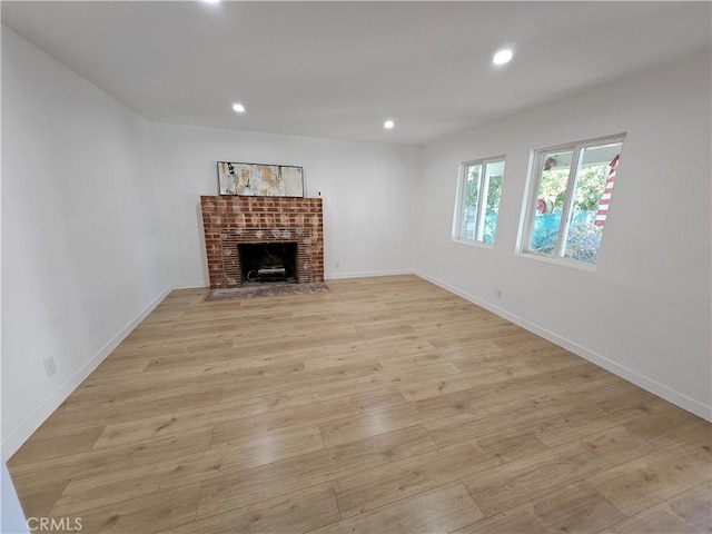 unfurnished living room with a fireplace, light wood-style flooring, recessed lighting, and baseboards