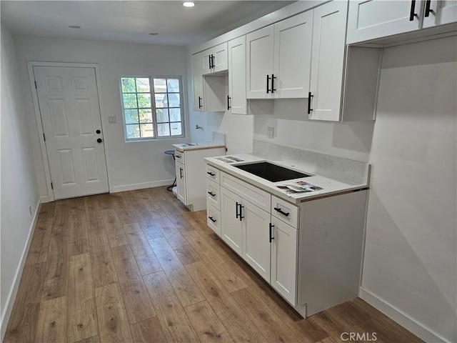 kitchen featuring light wood-type flooring, recessed lighting, white cabinets, light countertops, and baseboards