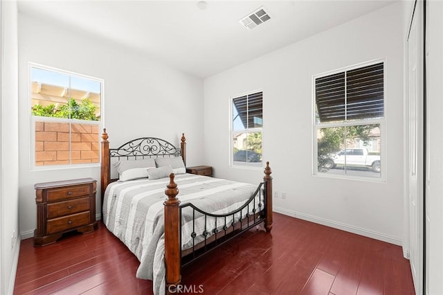 bedroom with multiple windows, dark wood-style floors, and visible vents