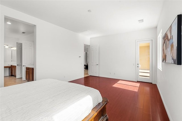 bedroom featuring visible vents, baseboards, wood finished floors, and ensuite bathroom