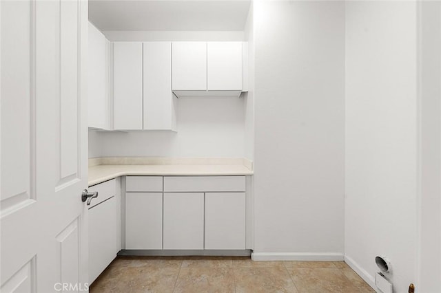 kitchen featuring white cabinets, light countertops, and baseboards