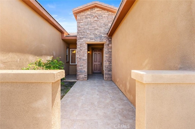 view of exterior entry with stucco siding and stone siding