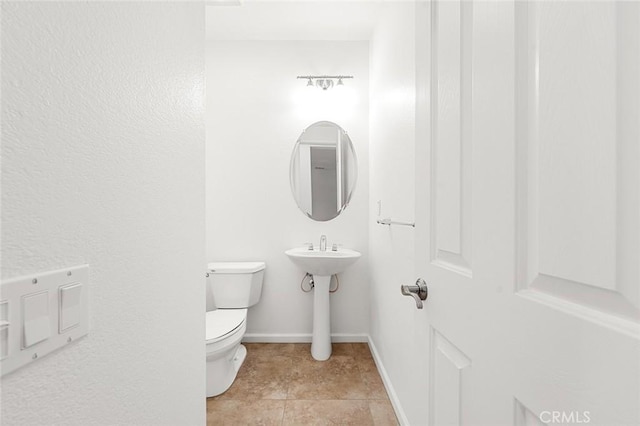 half bath featuring tile patterned floors, baseboards, and toilet