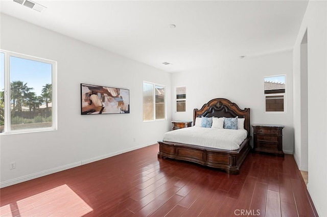 bedroom with visible vents, baseboards, and wood finished floors