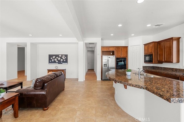 kitchen featuring black appliances, a breakfast bar, a sink, open floor plan, and recessed lighting