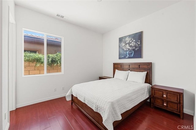 bedroom featuring visible vents, baseboards, and wood finished floors