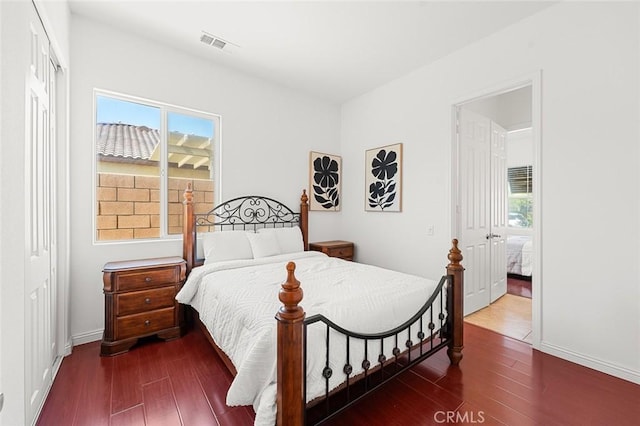 bedroom featuring multiple windows, wood finished floors, visible vents, and a closet