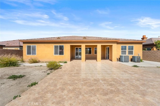 back of property featuring stucco siding, cooling unit, and fence