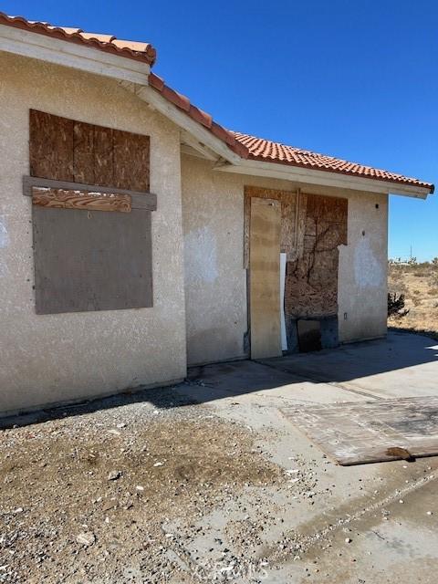 exterior space featuring a tile roof and stucco siding