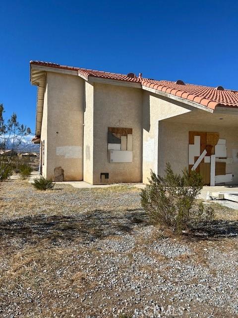 back of house featuring stucco siding and a tiled roof