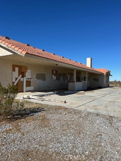 back of property with a tiled roof, a patio area, and stucco siding