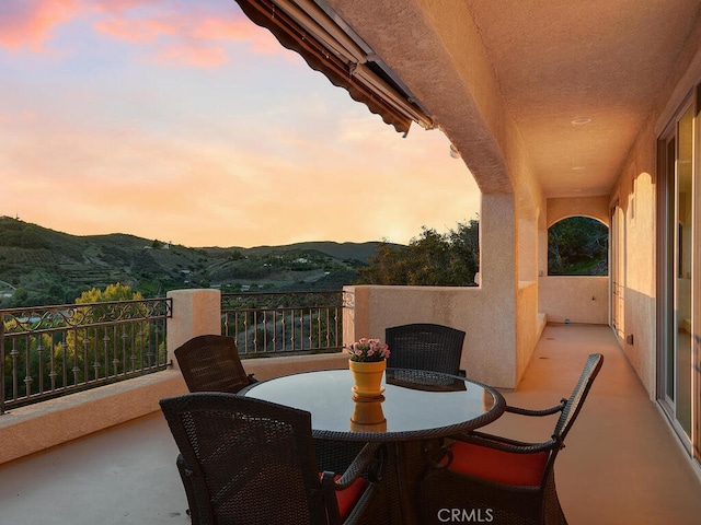 patio terrace at dusk featuring a mountain view and a balcony