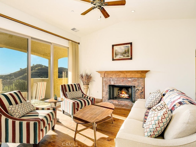 sitting room with a ceiling fan, wood finished floors, visible vents, a premium fireplace, and lofted ceiling