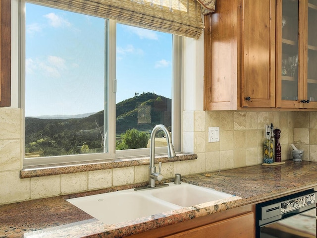 kitchen featuring a healthy amount of sunlight, a mountain view, brown cabinets, and a sink