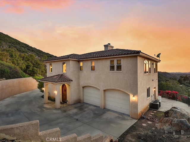 view of front of property with concrete driveway, an attached garage, a chimney, and stucco siding