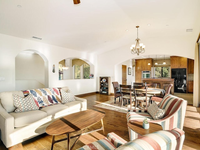 living room featuring an inviting chandelier, wood finished floors, visible vents, and baseboards