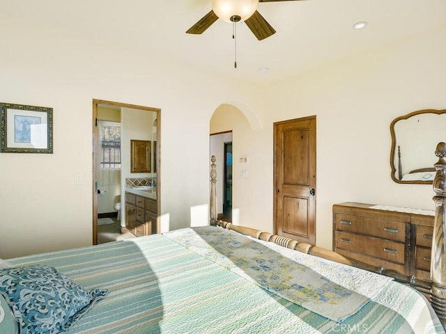 bedroom with a ceiling fan, arched walkways, and connected bathroom