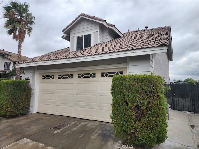 view of front of property with concrete driveway, a gate, a tile roof, and an attached garage